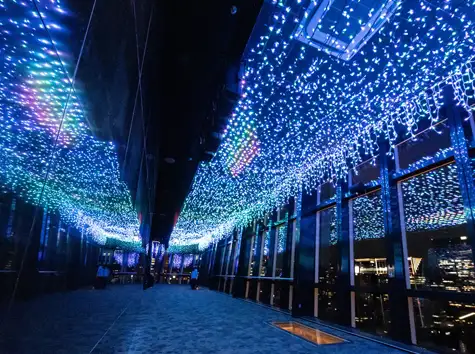 A Main Deck corridor overlooking the Tokyo night view, with blue light illumination spreading across the ceiling