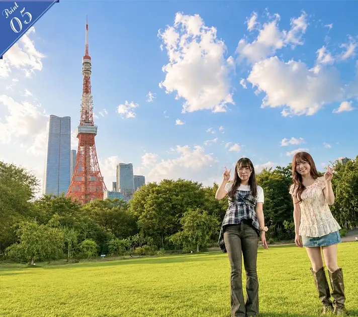 Two women holding hands and laughing together with Tokyo Tower in the background at Prince Shiba Park