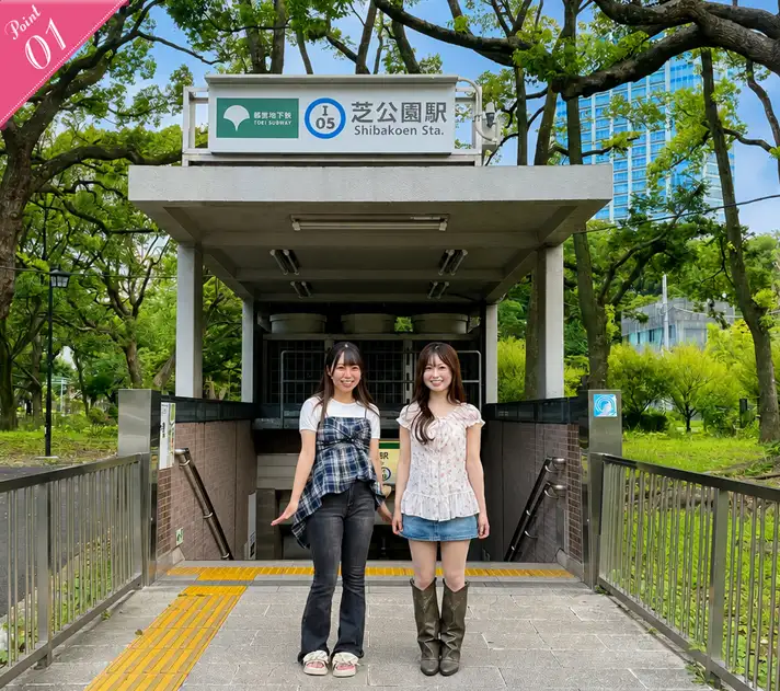 Two women smiling side by side at the entrance to Shibakoen Station on the Toei Mita Line