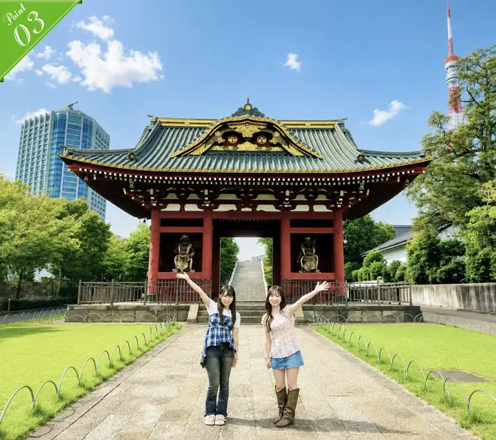 Two women throwing their arms up in front of the vermilion Somon Gate, with Tokyo Tower visible beyond