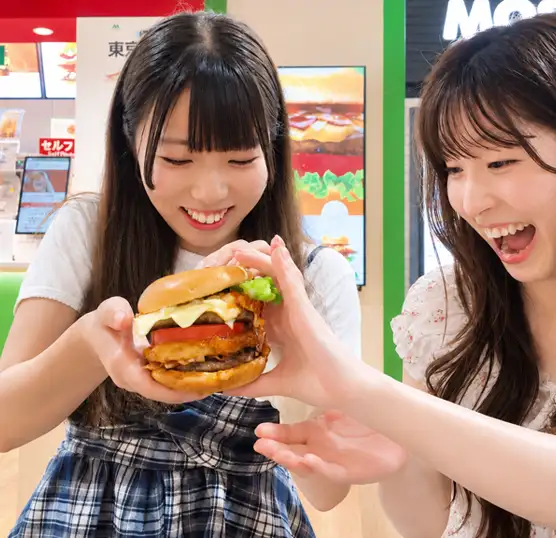 Two women smiling as they hold the store-exclusive Tokyo Tower Burger