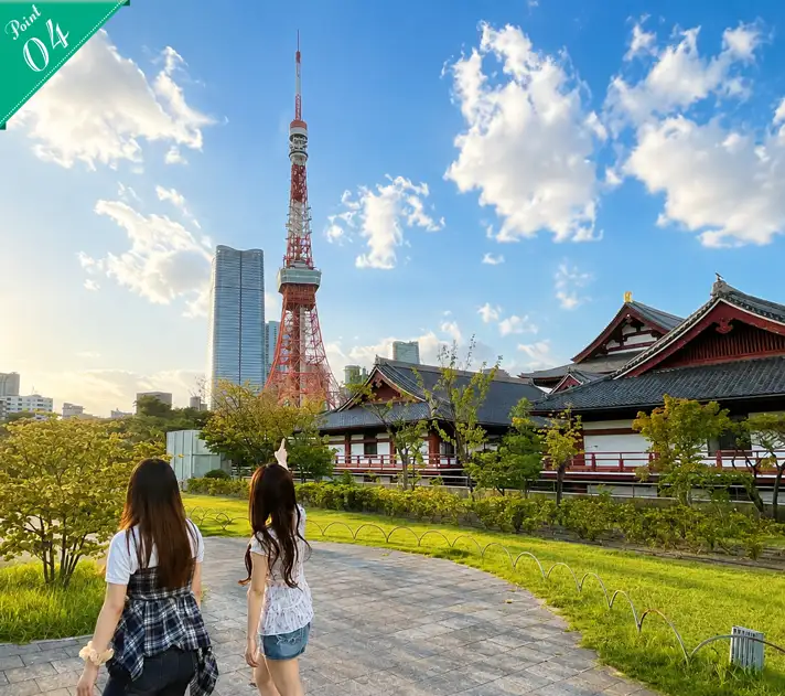 Two women seen from behind, walking and taking in the traditional buildings of Zojoji Temple alongside Tokyo Tower