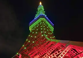 A close-up of Tokyo Tower's upper section lit up in red and green